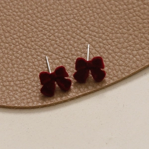 Gros plan sur les boucles d'oreilles nœud en velours rouge et tiges en argent
