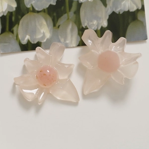 Makroaufnahme von rosa Blumenanhängern mit Goldfolie auf weißem Grund für DIY-Schmuck