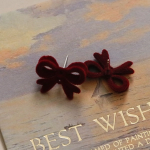Gros plan détaillé de boucles d'oreilles nœud en velours rouge foncé avec aiguilles S925