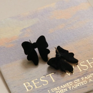 Gros plan sur une boucle d'oreille nœud noir floqué sur une carte de bijoux rétro