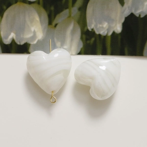 Macro shot of heart-shaped white marble resin beads for DIY jewelry making with gold pins