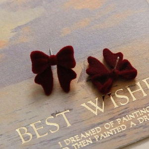 Gros plan élégantes boucles d'oreilles nœud floqué rouge vin avec aiguilles en argent S925