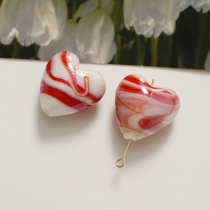 Detail of red and white marbled heart beads with golden metal hooks for DIY jewelry