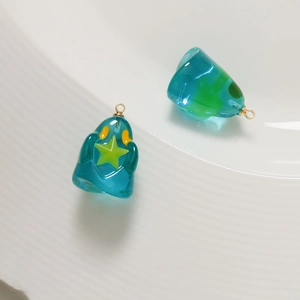 Detailed macro of translucent resin ghost pendants with gold rings on ceramic tray
