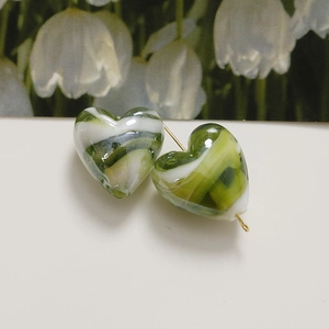 Detail of heart-shaped marble glaze beads with green and white swirls and gold pins