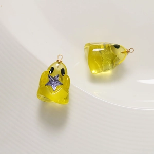Close-up of yellow resin ghost charms with purple star and golden ring for DIY jewelry
