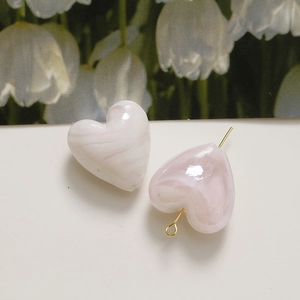 Macro view of heart-shaped beads with pink marble texture and gold metal pins for DIY