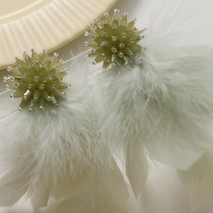 Detail of light green beaded star sphere and soft feather tassels for handmade jewelry