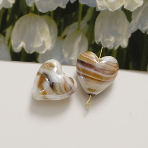 Detail of heart-shaped marble beads with caramel ink ripple pattern and golden pin