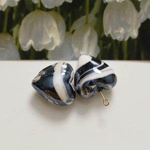 Macro detail of heart-shaped glass beads with black and white ink swirl patterns