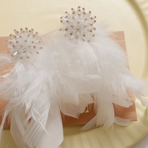 Close-up of white feather earrings with intricate bead clusters and silk ribbon details