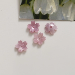 Close-up of pink cherry blossom acrylic flower beads with pearl luster for DIY jewelry