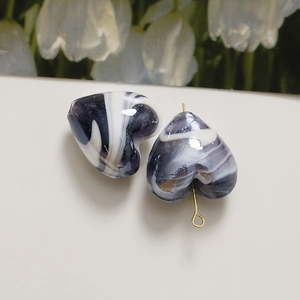 Macro shot of purple and white marbled heart glass beads with gold hook attachment