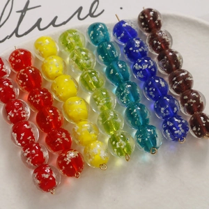 Dettaglio di perline in vetro luminoso da 12mm con connettori dorati per creazione gioielli