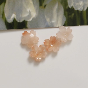 Close-up of four cherry blossom acrylic beads with center holes for DIY jewelry making