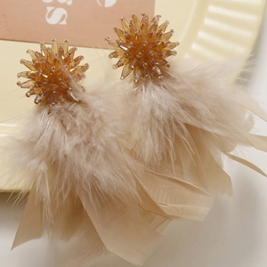 Bohemian style amber bead and light brown feather tassel earrings on a ceramic plate