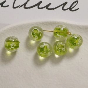 Vista macro di perle luminose verdi da 12mm con motivi bianchi su vassoio in ceramica