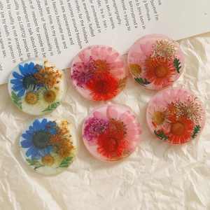 Flat lay of handmade resin charms with embedded real sunflowers and colorful dried petals