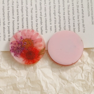 Macro shot of clear resin charms featuring real pink dried flowers for DIY jewelry making