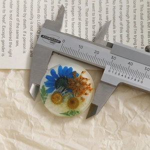Macro shot of a 25mm round transparent resin pendant with real dried flowers and calipers