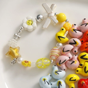 Makro-Detail bunter Keramik-Entenperlen und sortierter Charms für DIY-Schmuckherstellung