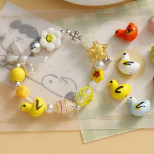 Detail eines bunten Keramik-Enten-Armbands mit Blumen-, Stern- und Kreuzanhängern