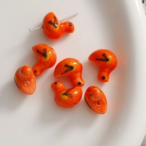 Nahaufnahme von orangefarbenen Keramik-Entenperlen mit glänzender Glasur für DIY-Schmuck