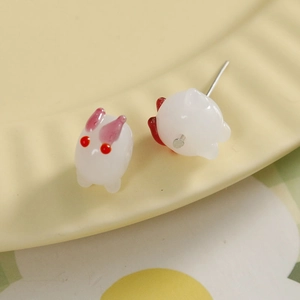 Gros plan de boucles d'oreilles lapin blanc avec oreilles roses sur un motif floral frais