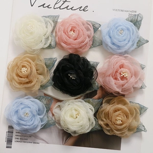 Close-up of nine colorful mesh fabric camellia flowers with pearl centers for DIY accessories