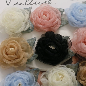 Flat lay of multi-color mesh and silk camellia flower charms with pearl centers for DIY crafts