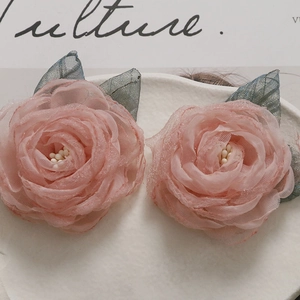 Detail of pink mesh fabric rose flower with white stamens and gray leaf accessories