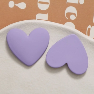 Close-up of purple matte resin heart-shaped jewelry charms on a white ceramic plate