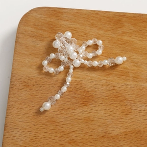 Detalle macro del accesorio de lazo hecho a mano con perlas blancas y cuentas de cristal