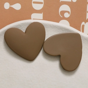 Macro shot of matte chocolate brown resin heart charms on a white ceramic plate