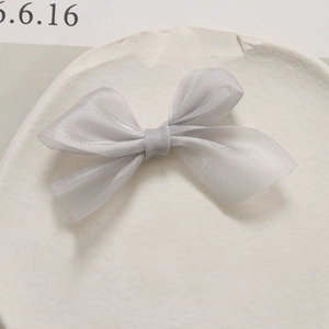 Detailopname van een lichtgrijze mesh-strik van zachte organza op een stenen dienblad