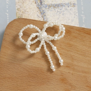 Detalle de lazo de perlas tejido a mano con elegantes flecos sobre fondo de madera