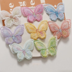 Détail de barrettes papillon brodées double couche colorées sur une assiette blanche