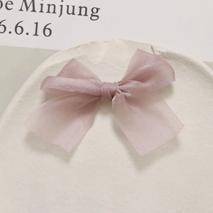 Detail van lichtpaarse organza strik accessoire op een minimalistische witte steen