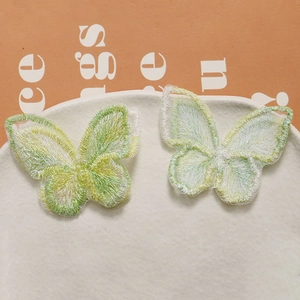 Détail de pinces à cheveux papillon en tulle brodé vert dans un plat en céramique