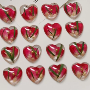 Detailed grid of resin heart charms with red dried flowers and gold beads for DIY crafts