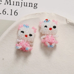 Dettaglio di ciondoli a forma di gatto in perline fatti a mano con abiti rosa e blu su piatto