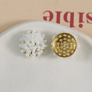 Handmade white beaded flower cluster earrings with golden base on a ceramic tray