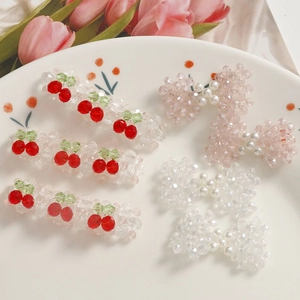 Détail de barrettes à perles faites main avec nœuds roses et cerises sur une assiette