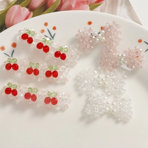 Détail de barrettes à cheveux avec nœuds roses et cerises en perles de verre et nacre