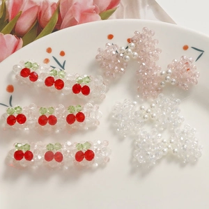 Détail de barrettes perlées avec perles roses, nœuds et motifs cerise sur une assiette
