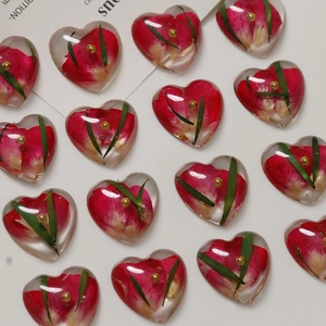 Detailed view of heart-shaped resin charms with real dried red flowers and gold beads