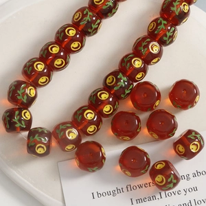 Detailed view of 14mm reddish-brown resin beads with yellow smiley face and leaf patterns