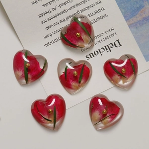 Handmade heart-shaped resin charms with red rose petals and green leaves for DIY jewelry