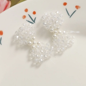 Détail d'une barrette faite main avec perles transparentes et perles blanches en forme de nœud