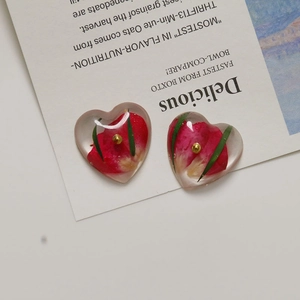 Detail of heart resin earrings with red rose petals and gold foil flakes